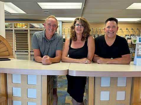 The three owners smiling for a photo in the showroom